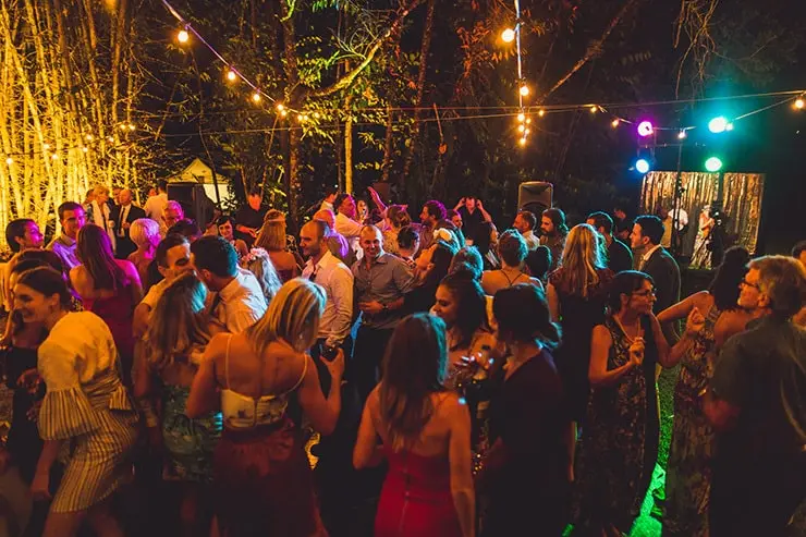 Drukke dansvloer op een verjaardagsfeest in de buitenlucht met kleurrijke verlichting en een DJ in de achtergrond